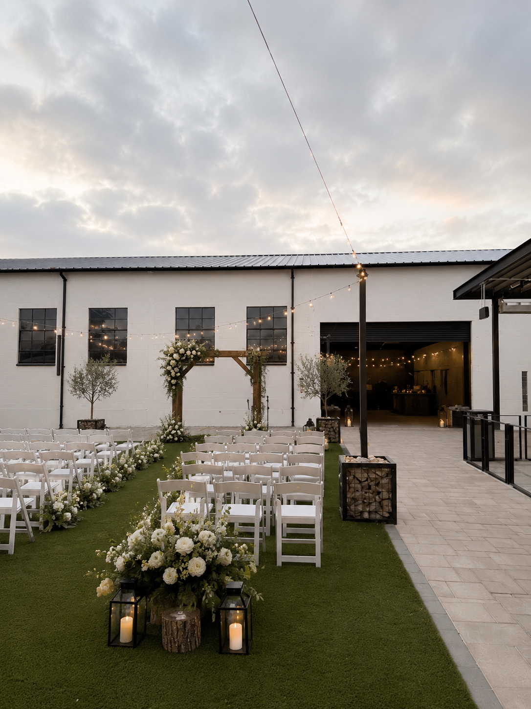 Outdoor courtyard ceremony with white chairs at sunset